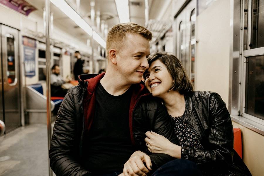 Casal sorrindo no metrô abraçados, mas preocupados com infertilidade