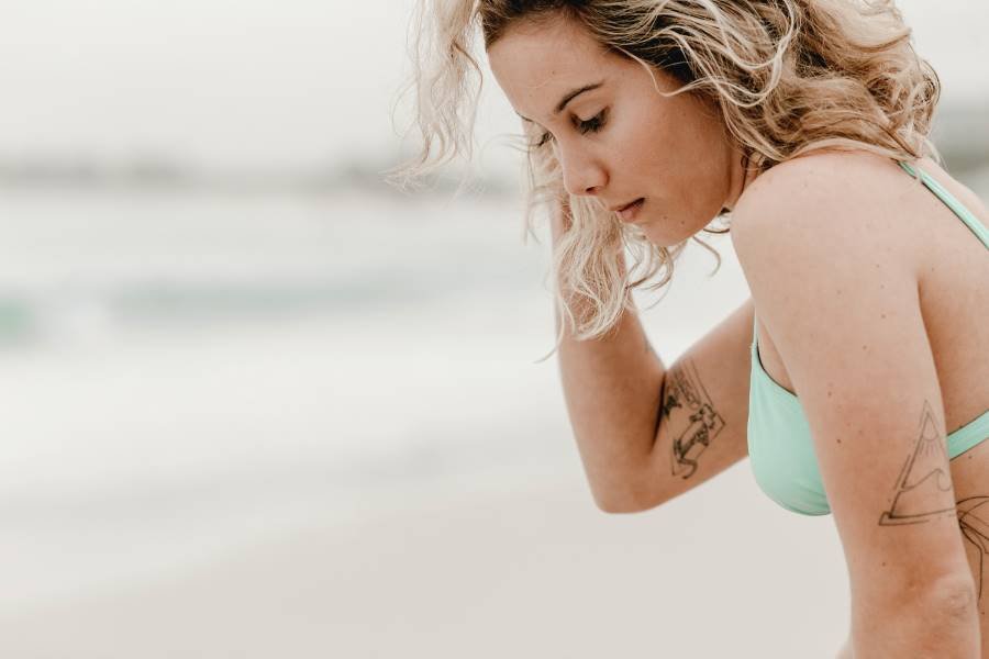Mulher na praia com ar preocupado pelas dores da endometriose